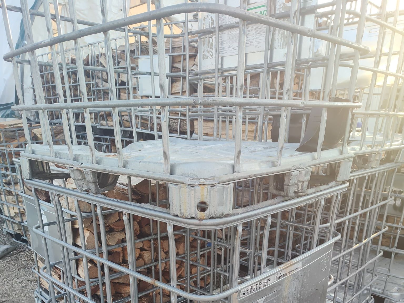 Close view of split firewood packed through the mesh of an IBC cage