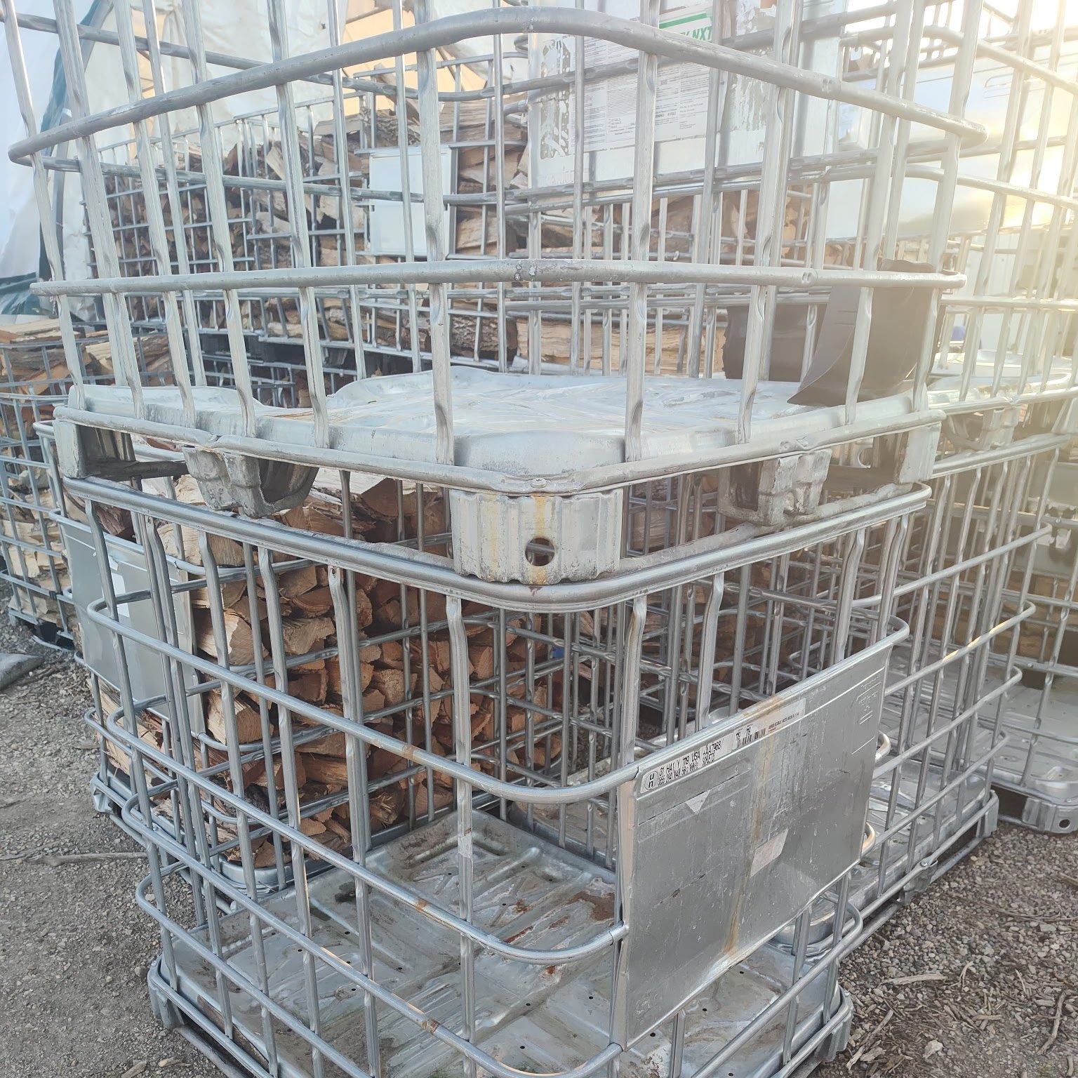 Galvanized IBC cage stacked with split firewood, seen square on